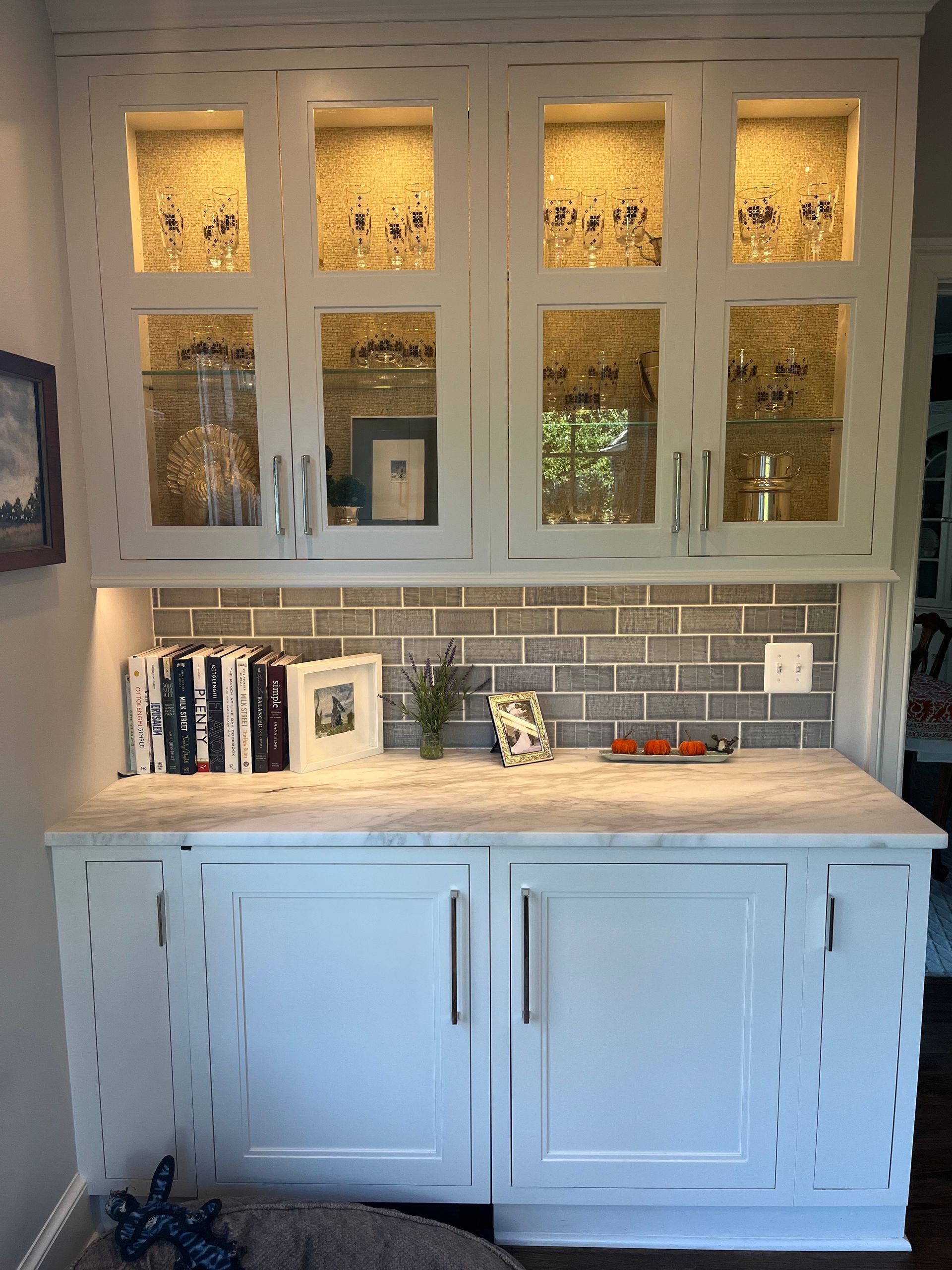 A kitchen with white cabinets and a tile wall.