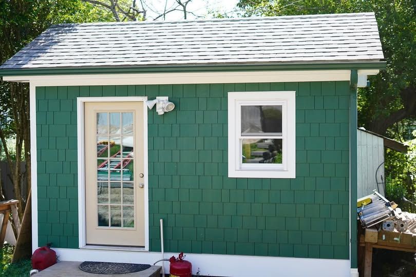 A small green house with a white door and window