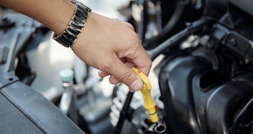 Man checking oil level with dipstick on car