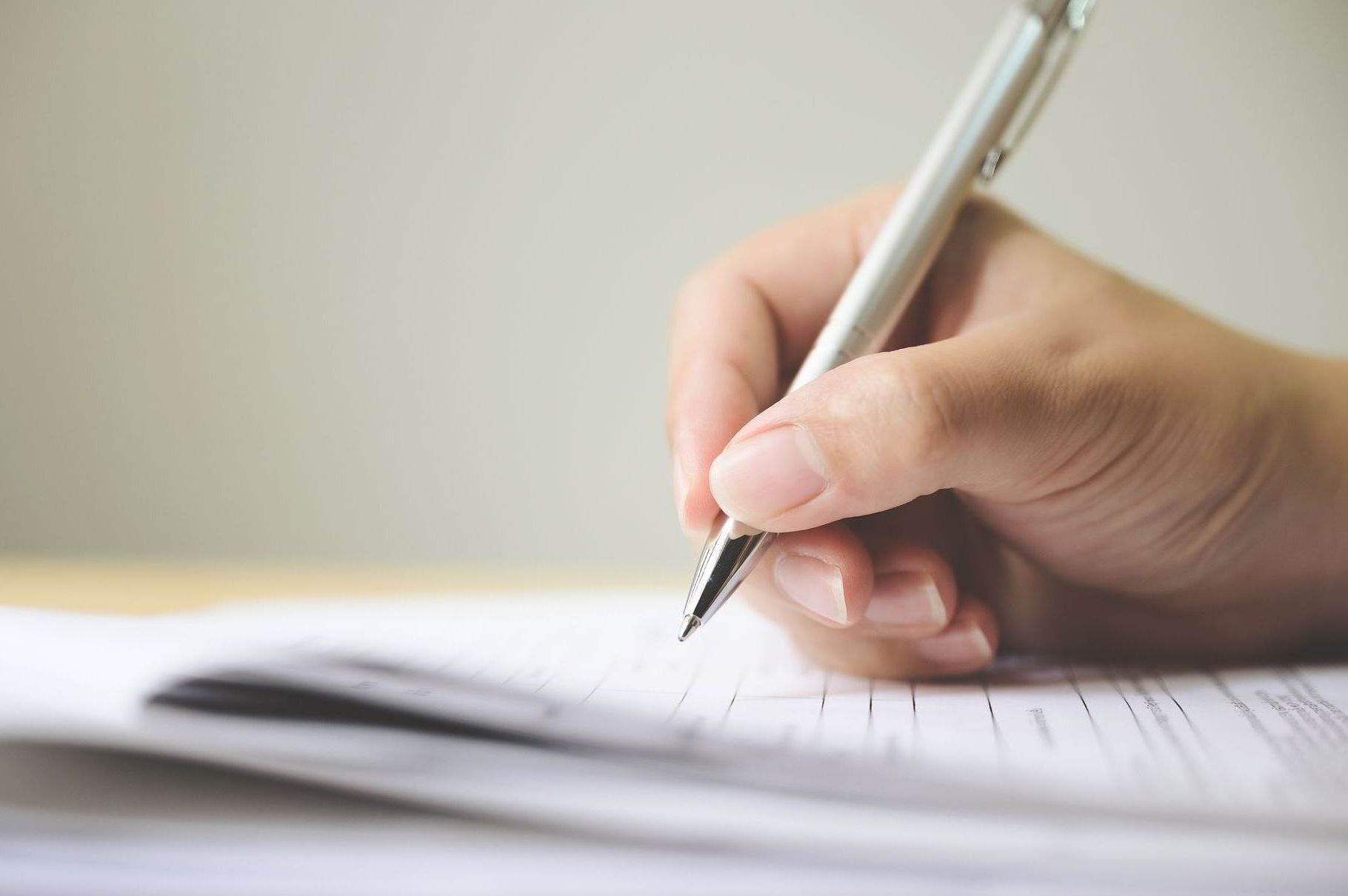 A person is writing on a piece of paper with a pen.