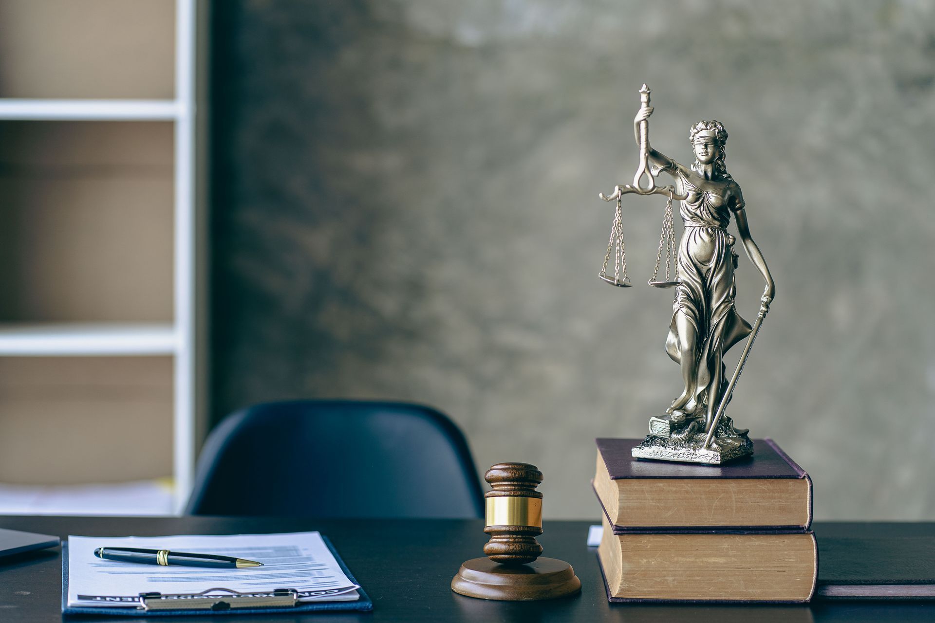 A statue of justice is sitting on top of a stack of books on a desk.