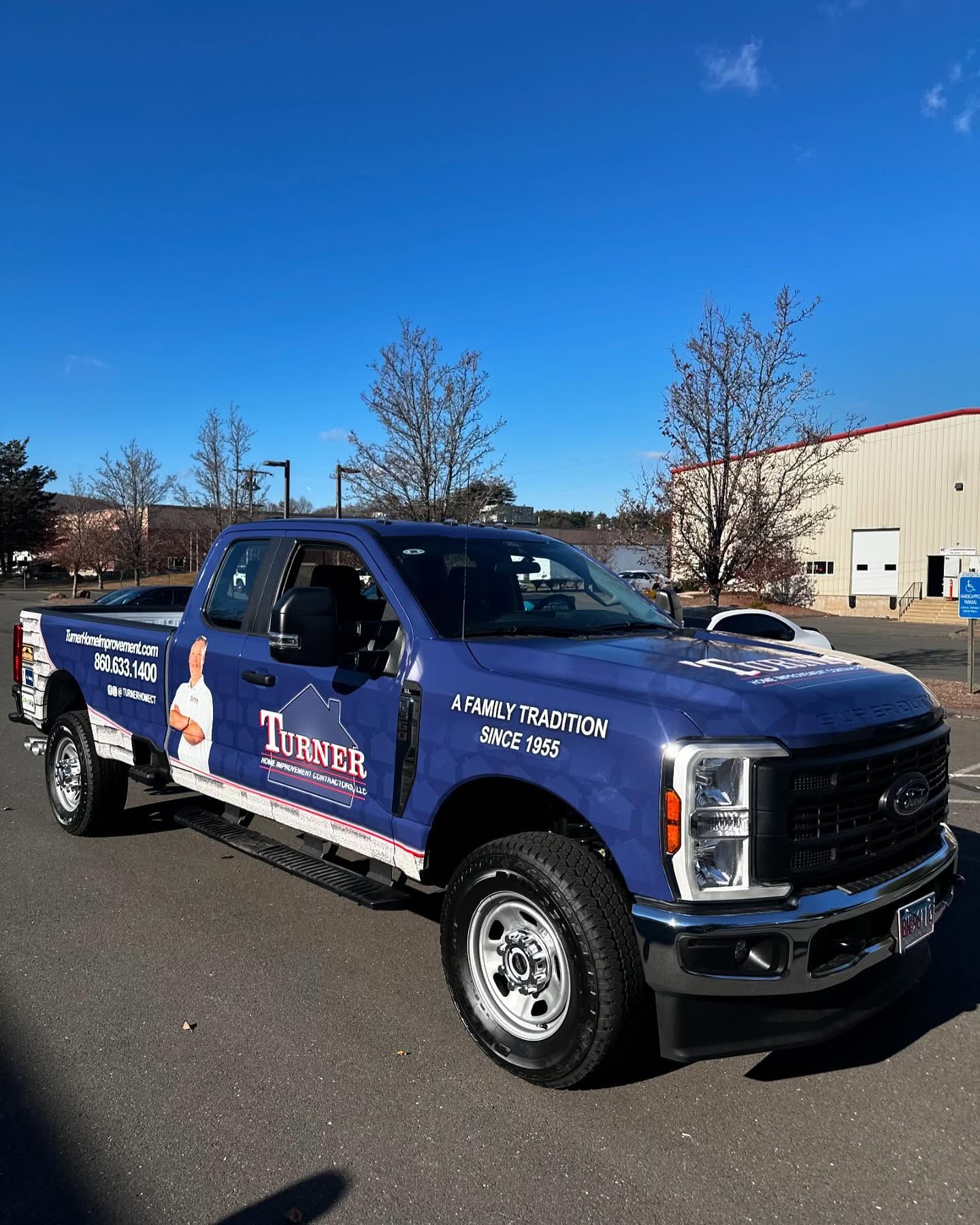 A blue truck with the word turner on the side is parked on the side of the road.