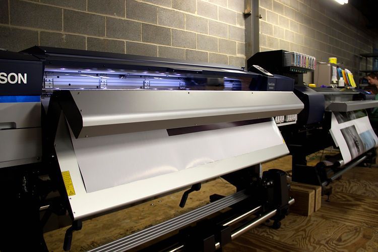 A row of epson printers are sitting in a warehouse.