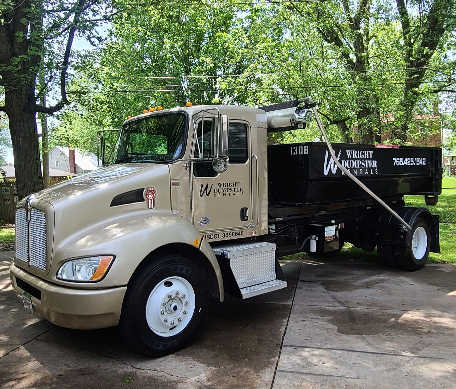 a dump truck is parked in a driveway with trees in the background .