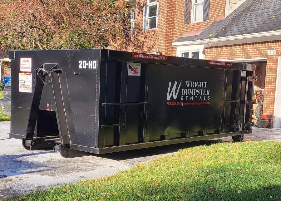 a large black dumpster is parked in front of a brick house .