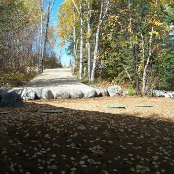 chemin de gravier qui mène à un terrain plat entouré d'arbres