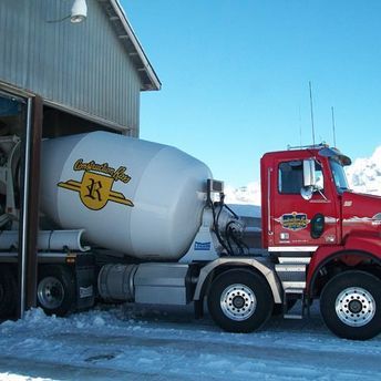 camion à béton avec logo de construction ross qui sort d'un garage