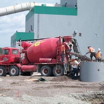 camion à béton qui déverse béton et ouvriers qui travaillent