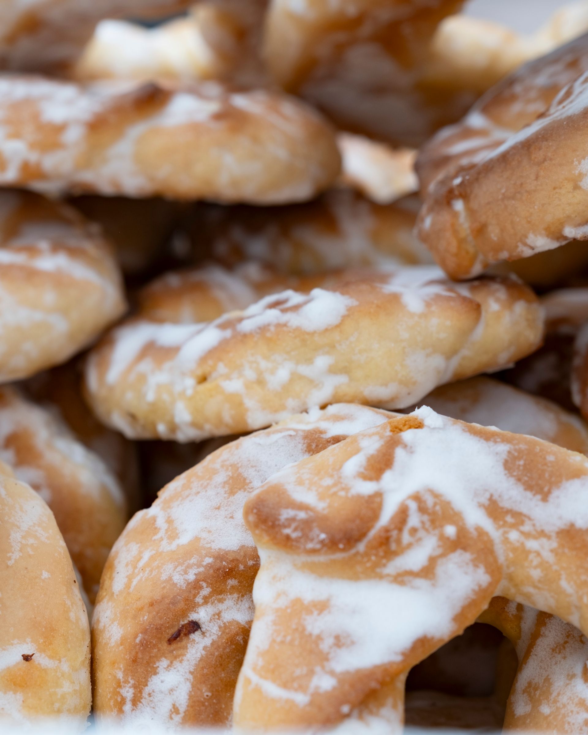 Mucchio di biscotti glassati, color nocciola chiaro, con glassa bianca.