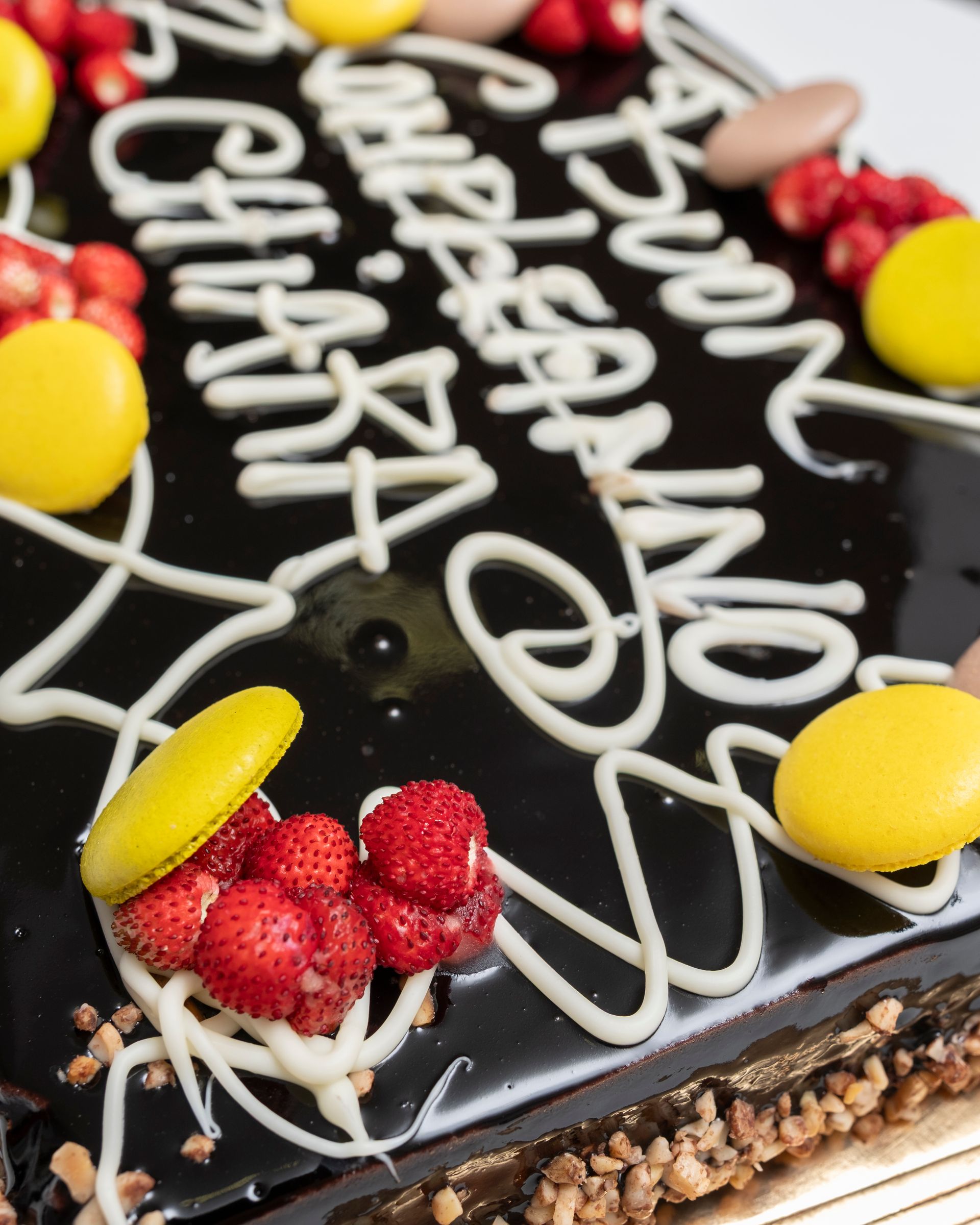 Torta al cioccolato con glassa bianca, macarons gialli, fragole e noci. Testo:
