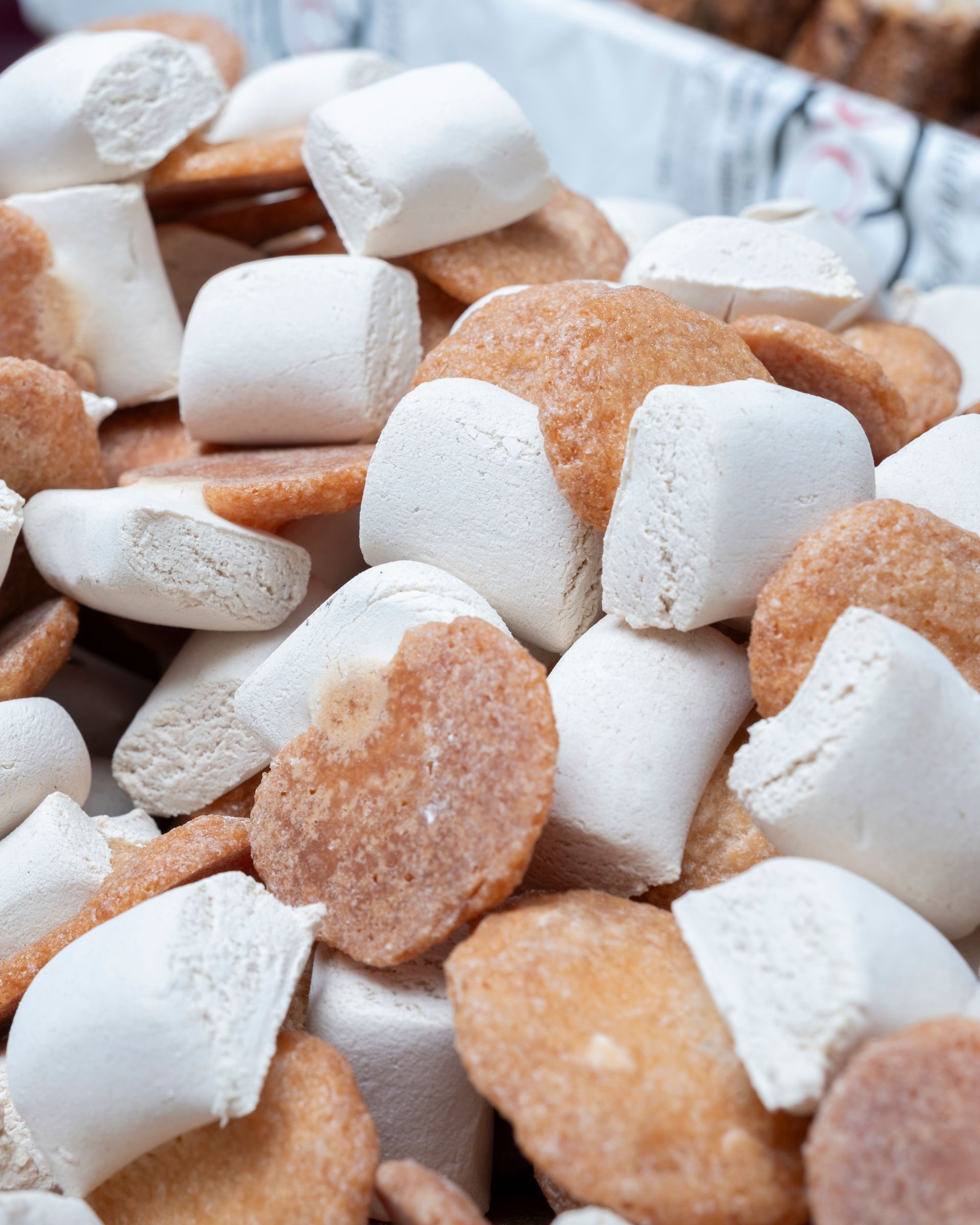 Mucchio di caramelle dure, bianche e marroni, quadrate e rotonde.