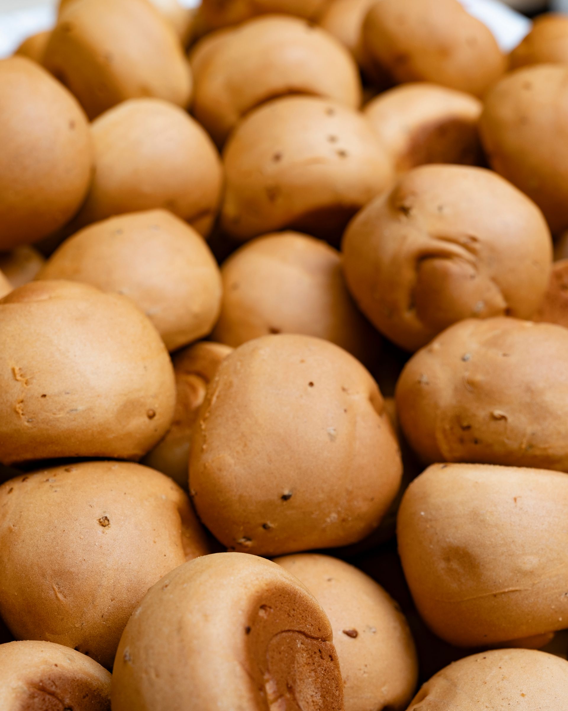 Primo piano di una pila di panini rotondi e dorati appena sfornati.