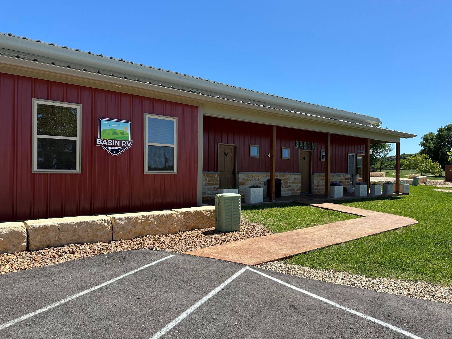 A large red building with a porch and a parking lot in front of it.