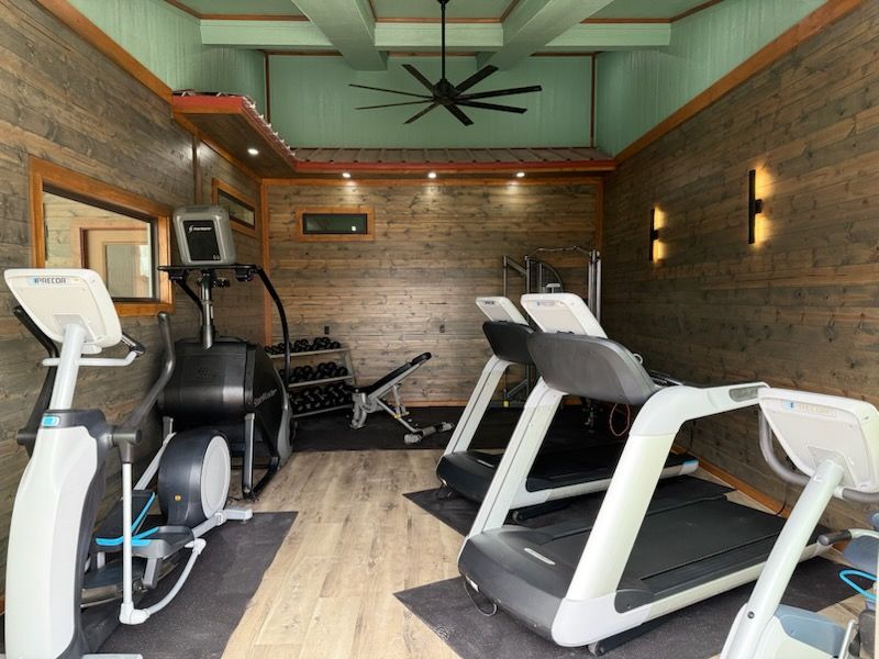 A rv is parked in a gravel lot with chairs and umbrellas.