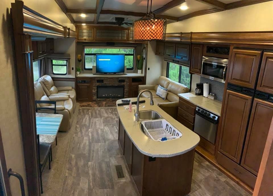 The inside of a rv with a living room and kitchen.