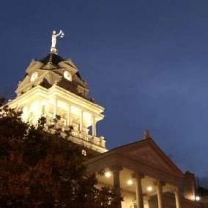 A large building with a statue on top of it at night.