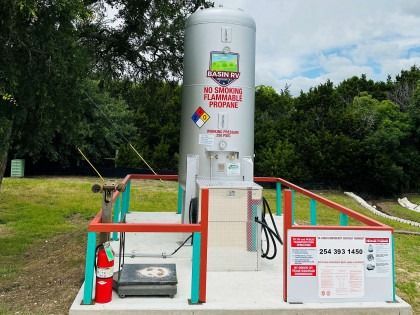 A large propane tank is sitting on top of a concrete platform.