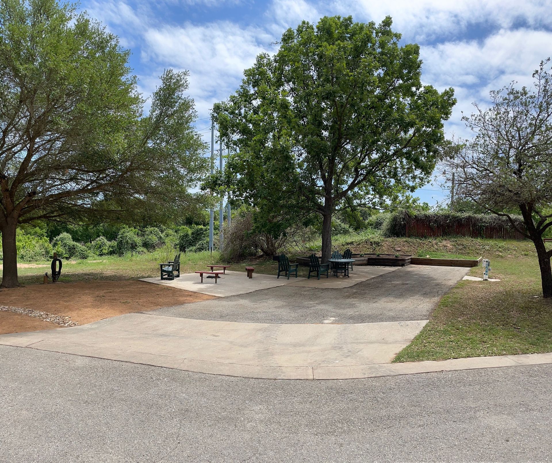 A park with a picnic table and benches under a tree.