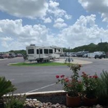 A rv is parked in a parking lot next to a picnic table.