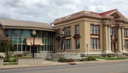 A large building with a lot of windows is sitting on the side of the road.