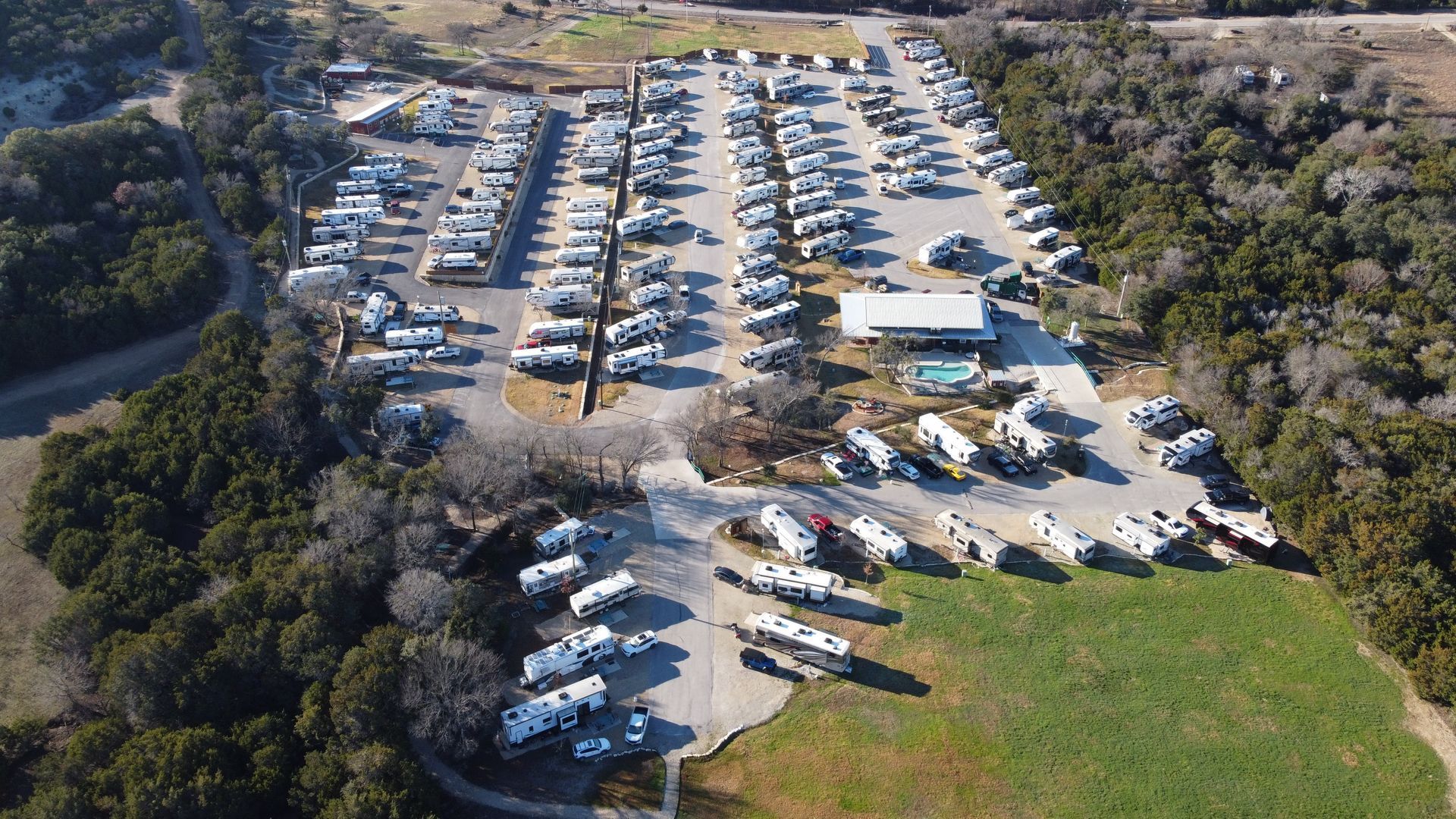 An aerial view of a rv park surrounded by trees and grass.