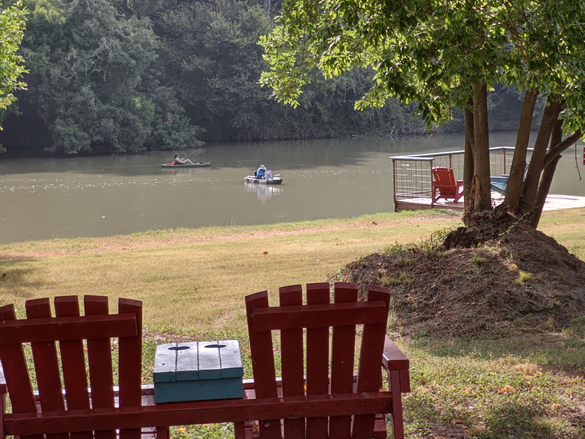 Three people are fishing on a dock at sunset