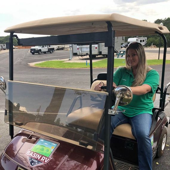 A woman in a green shirt is sitting in a golf cart.