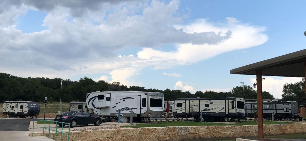 A row of rvs are parked in a parking lot under a covered area.