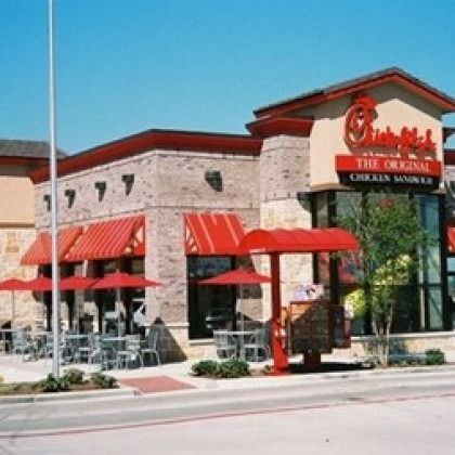 A chick-fil-a restaurant with red awnings and tables