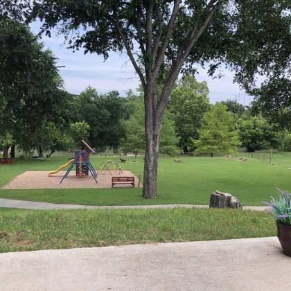 A view of a park with a playground and trees