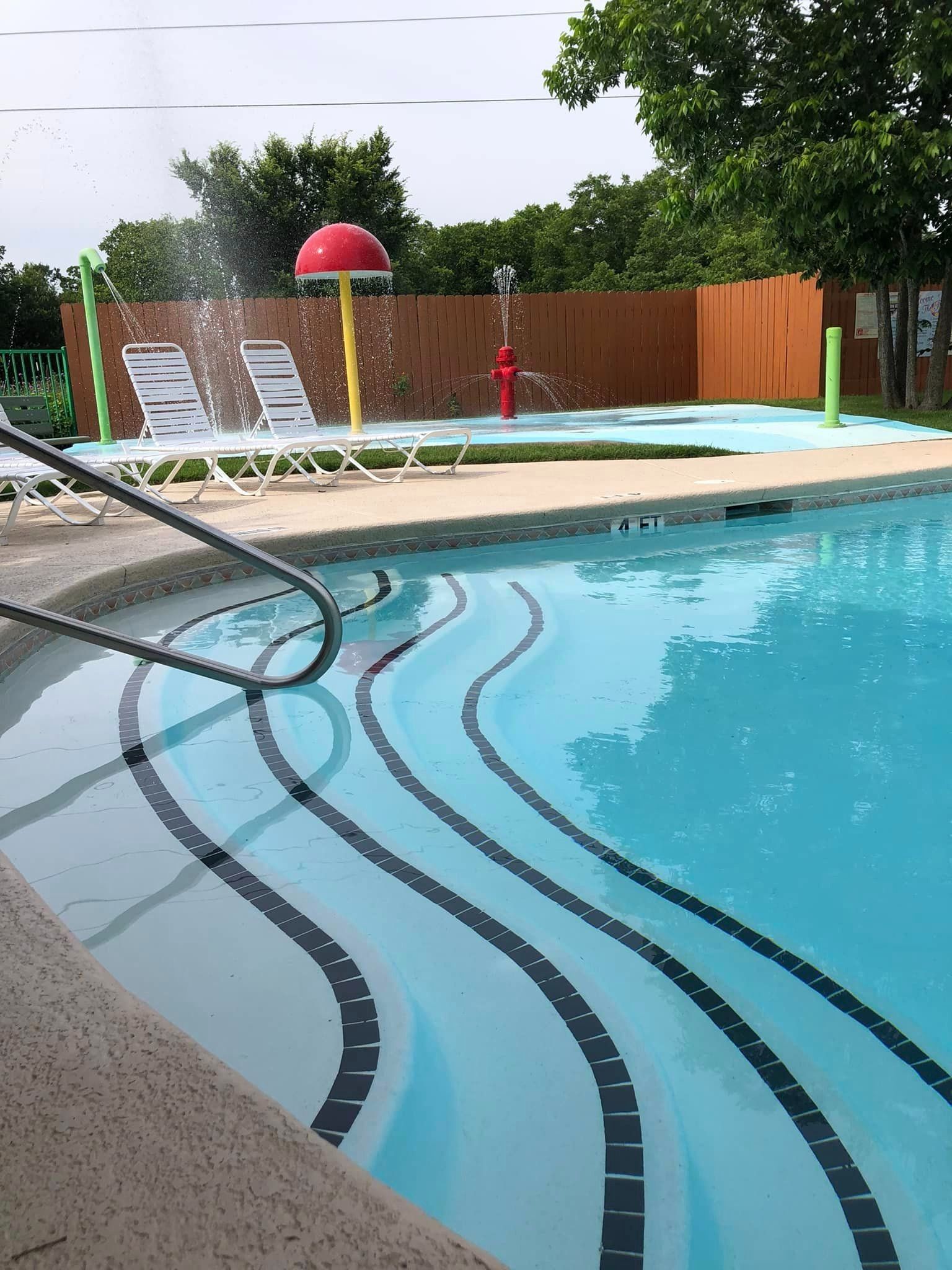A swimming pool with a fence and chairs in the background