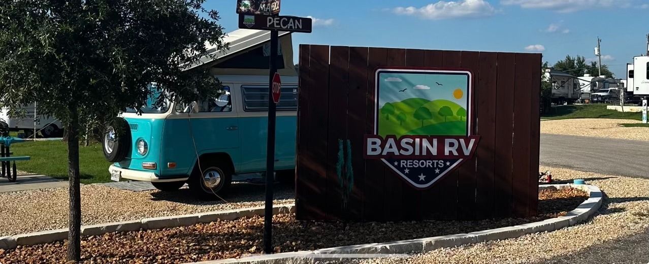 A blue van is parked in front of a sign that says basin rv.