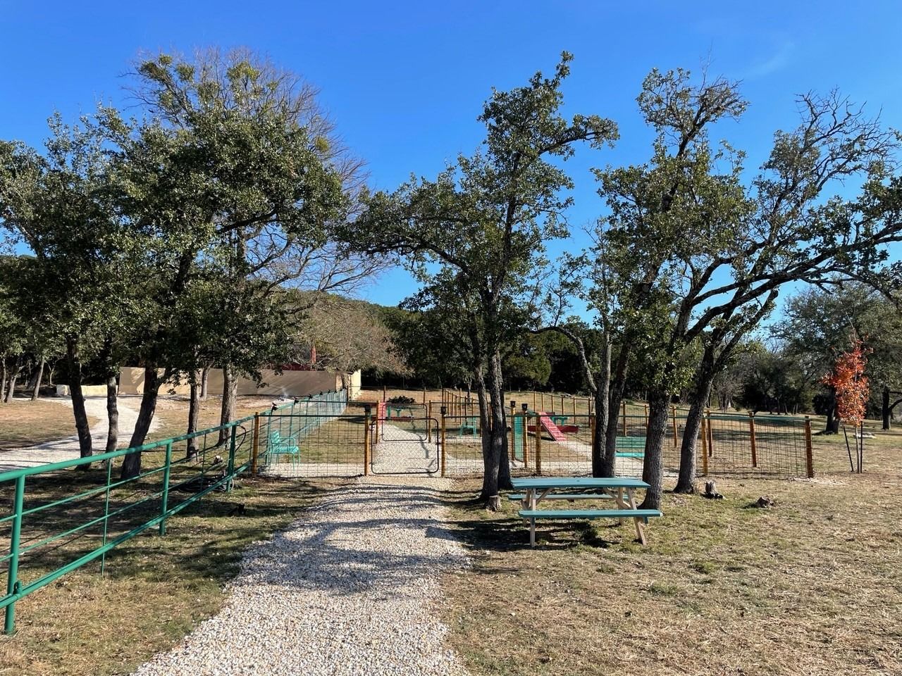 A path leading to a park with trees and a picnic table.