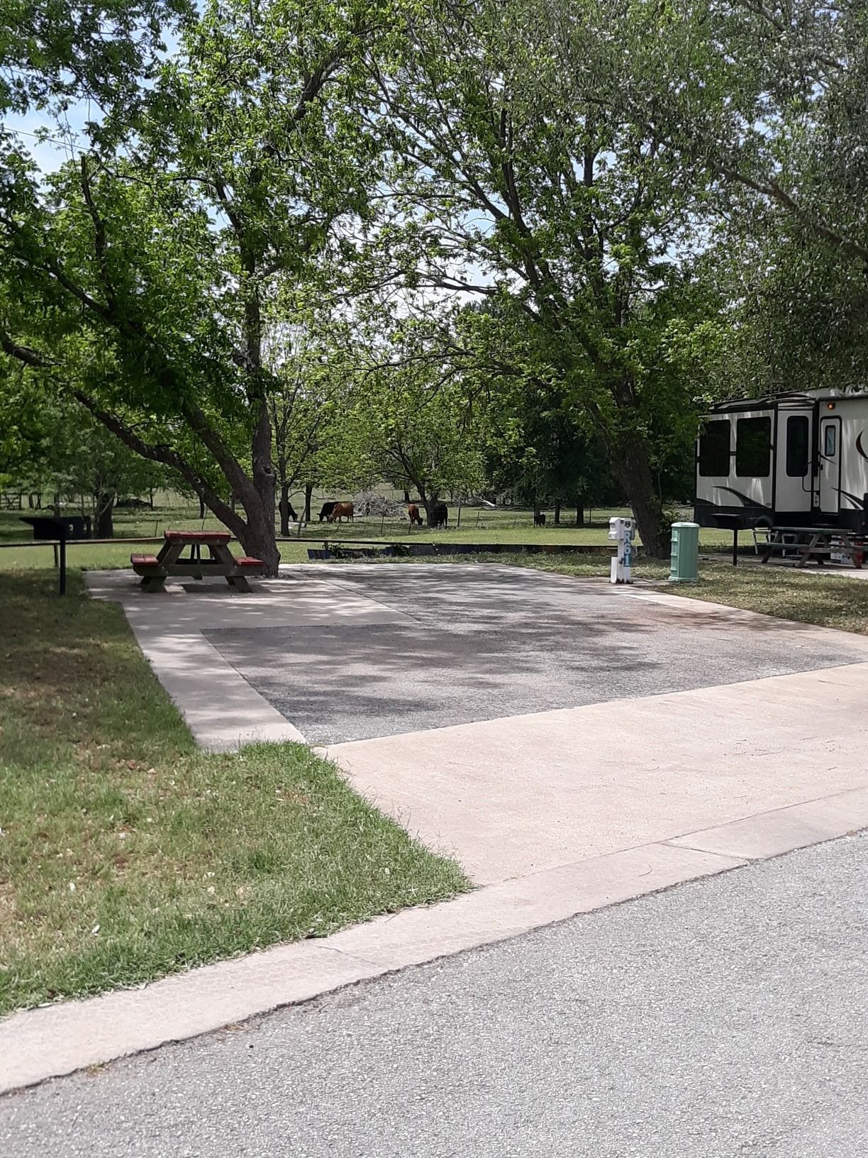 A rv is parked on the side of the road next to a picnic table.