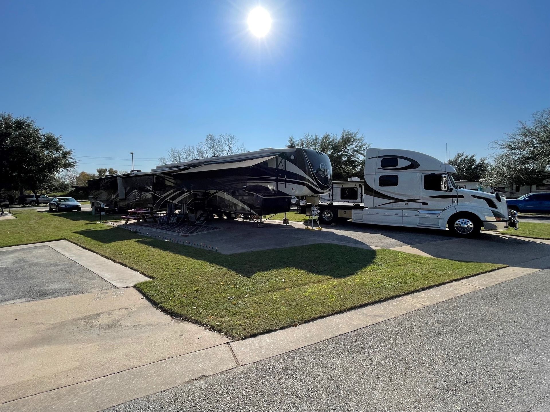 A rv is parked in a grassy area next to a truck.