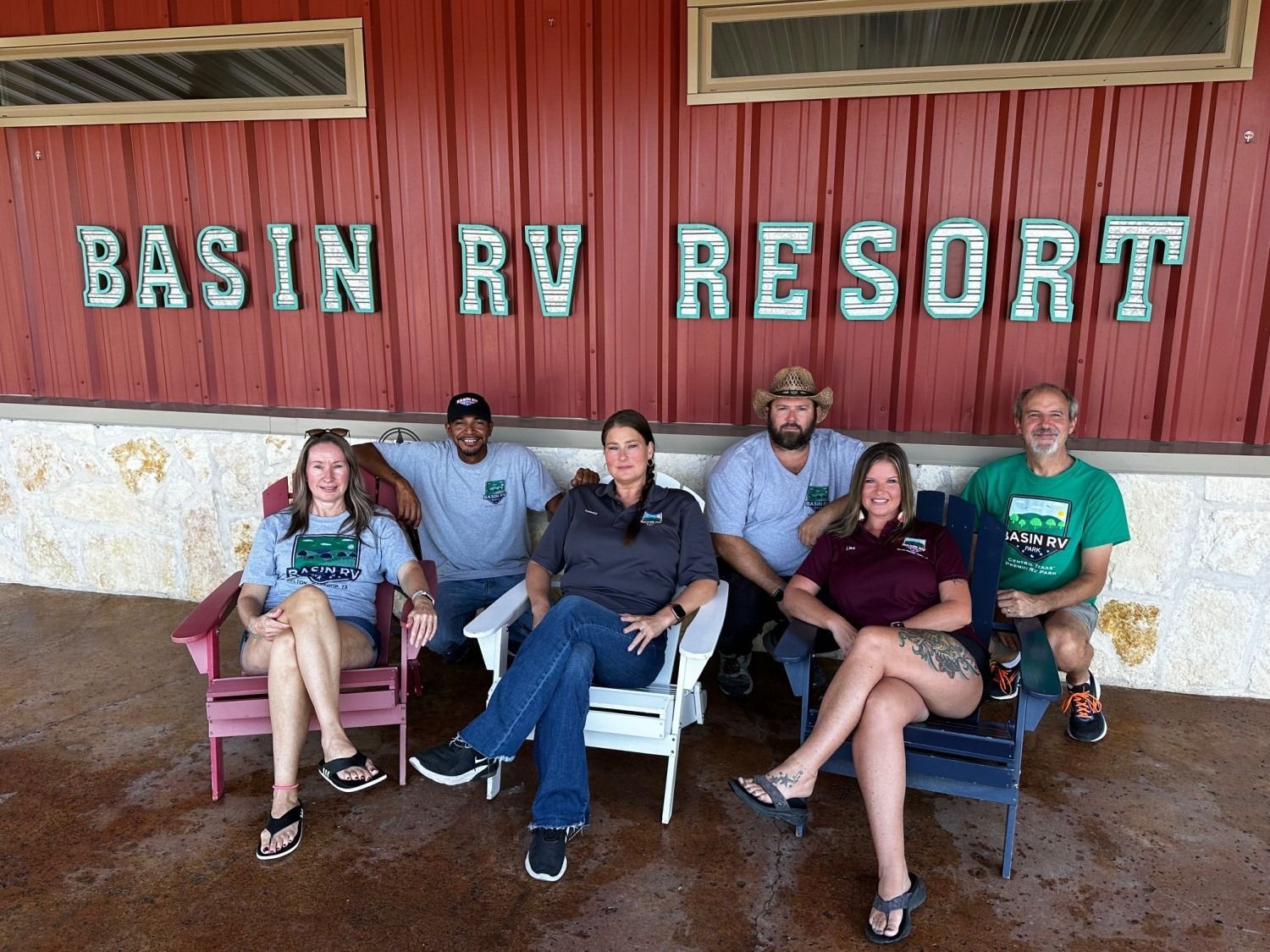 A group of people sitting in chairs in front of a sign that says basin rv resort