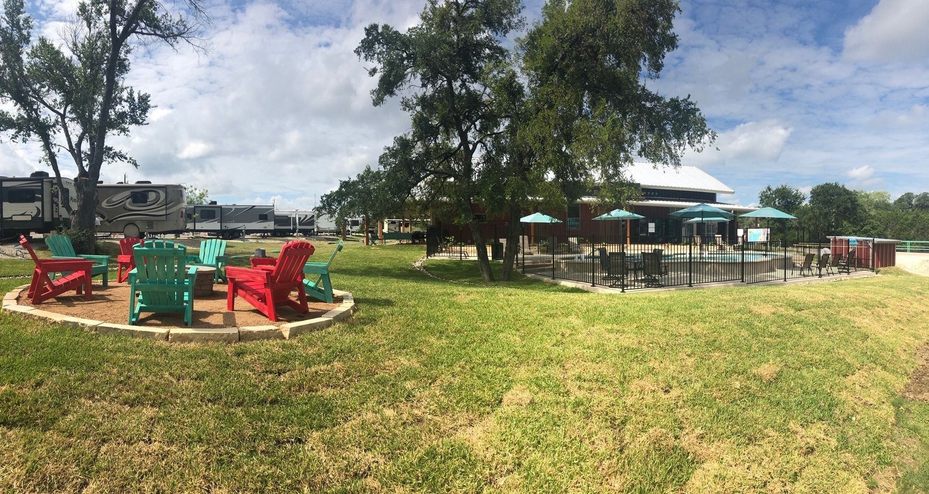 A group of chairs are sitting around a fire pit in a grassy field.