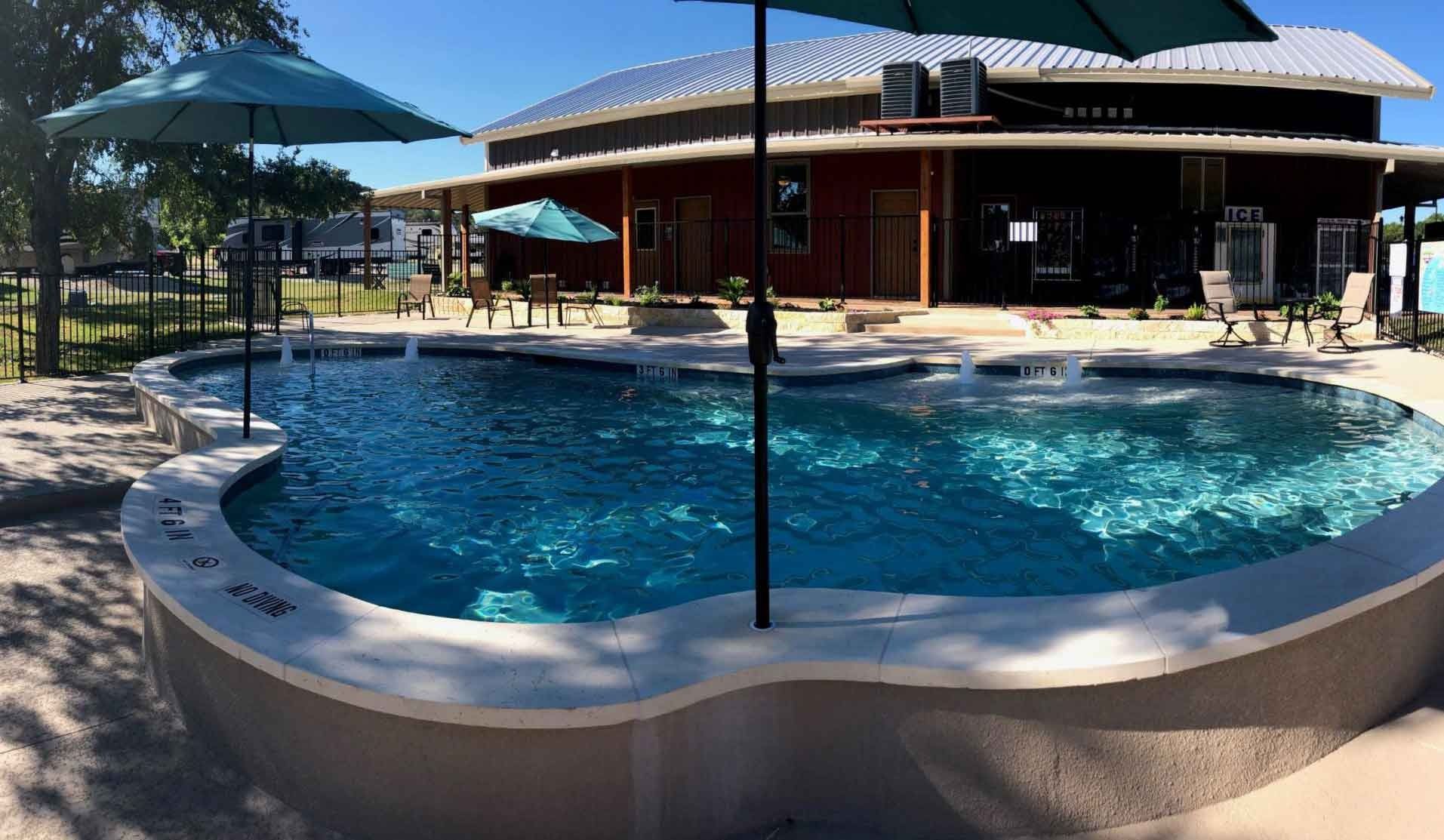 A large swimming pool with umbrellas in front of a building