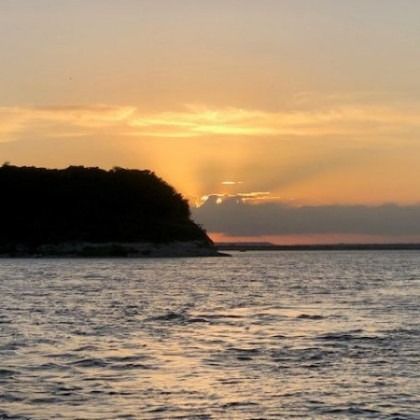 A sunset over a body of water with a small island in the distance