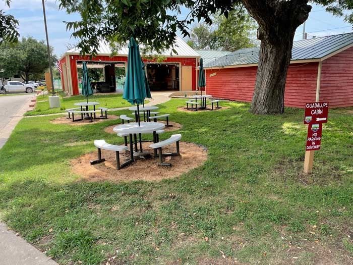 A picnic area with tables and umbrellas in front of a building.