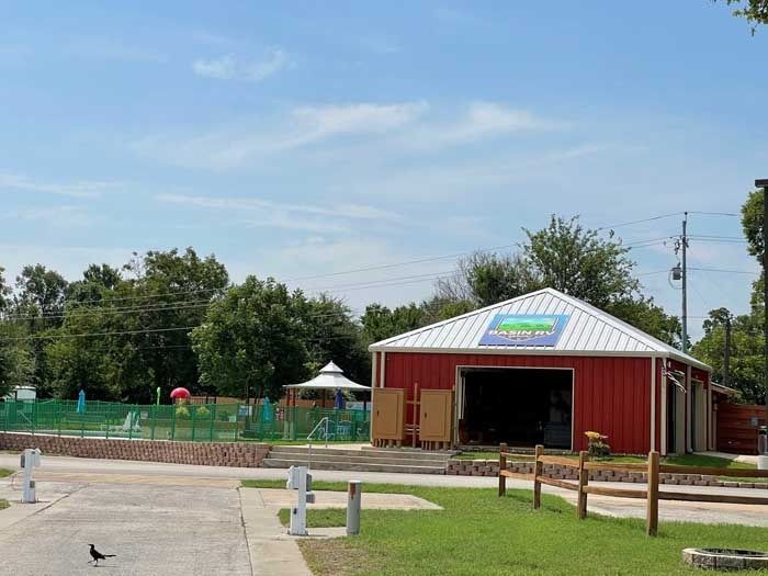 A red barn with a white roof is in the middle of a park.
