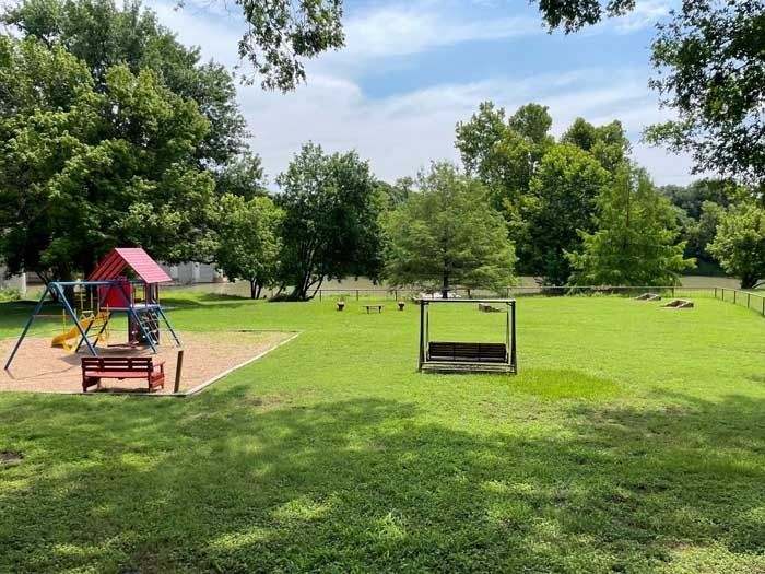 There is a playground in the middle of a lush green field.