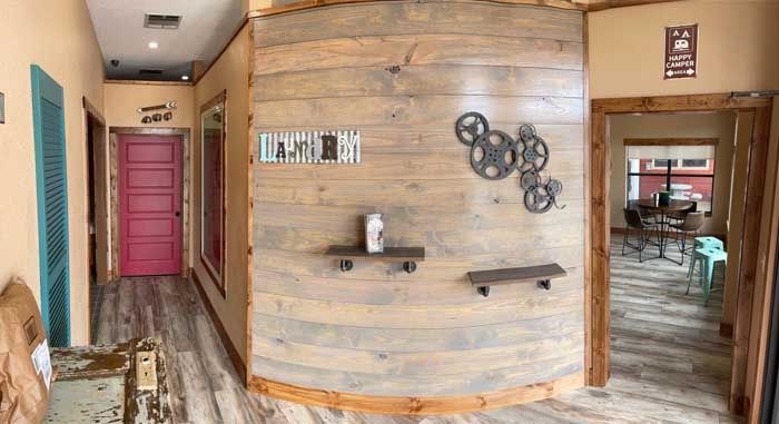 A long hallway with a wooden wall and a pink door.