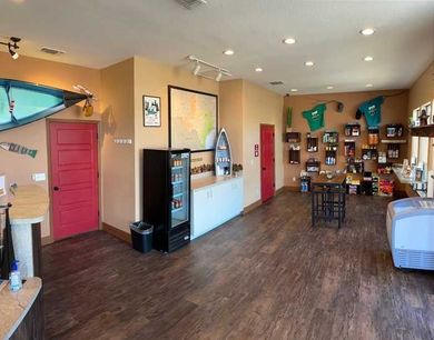 A large room with wooden floors and a refrigerator.