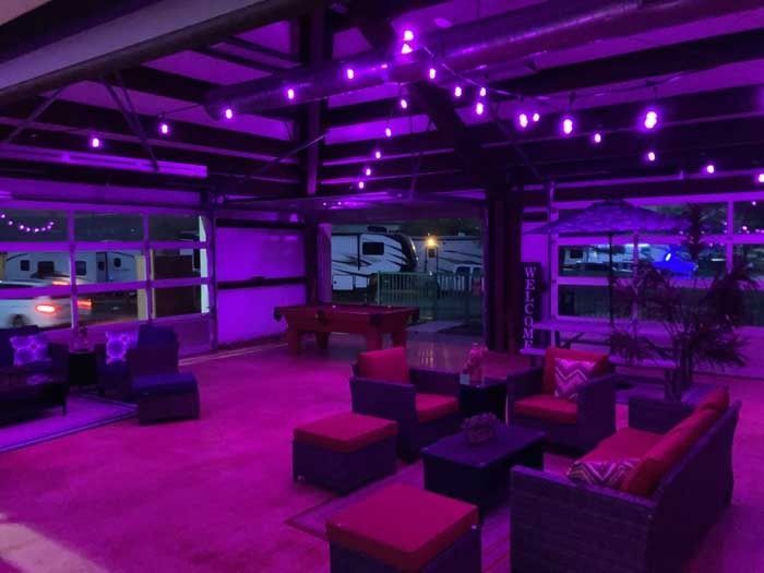 A living room with purple lights and a pool table
