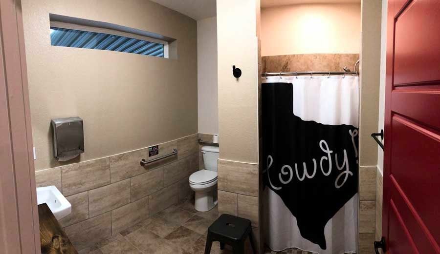 A bathroom with a toilet , sink , shower curtain and a red door.