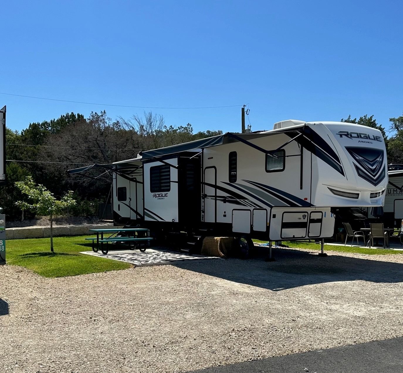 A white rv is parked in a gravel lot