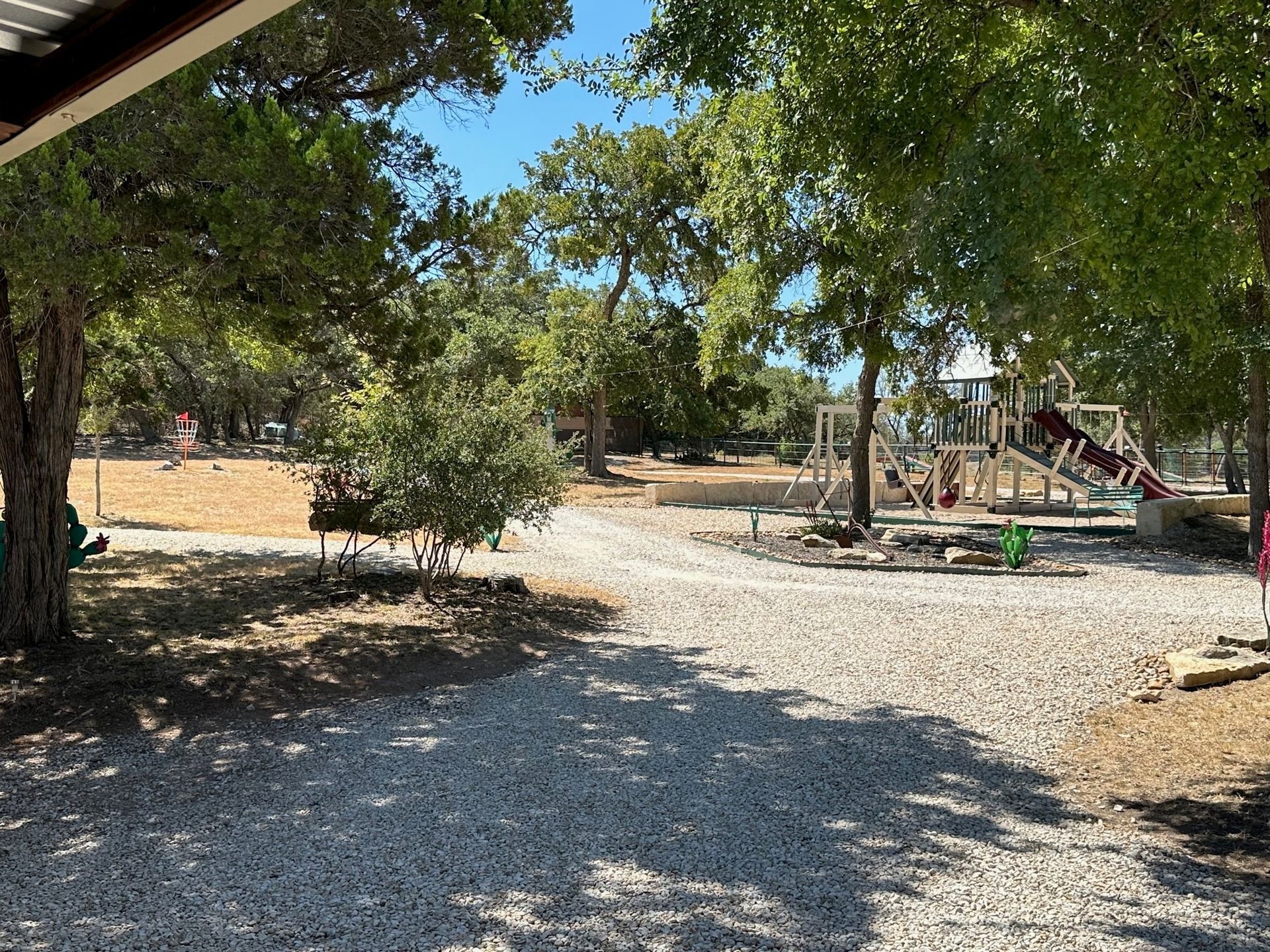 A playground is surrounded by trees and gravel in a park.