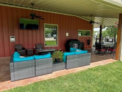 A patio area with a couch , chairs , table and television.