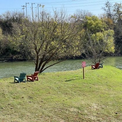 A group of chairs are sitting in a grassy area next to a river.